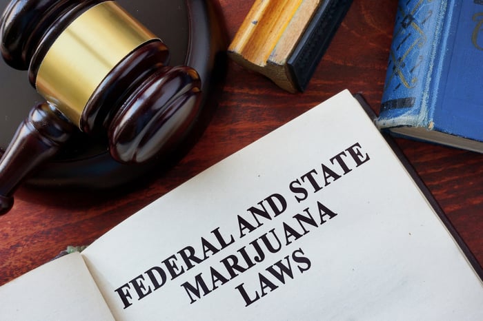 A judge's gavel next to a book containing federal and state marijuana laws. 