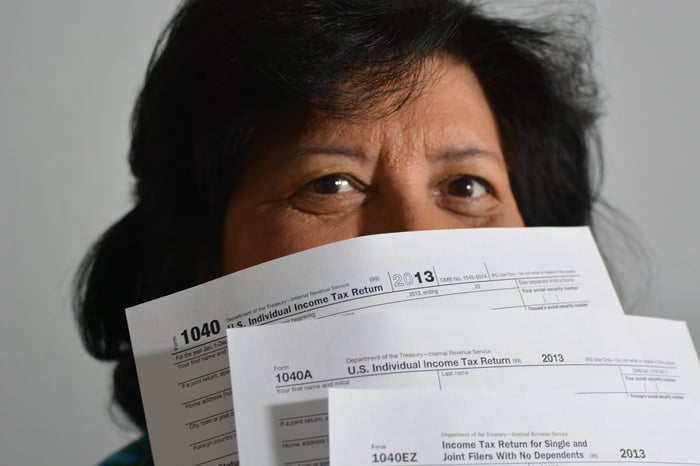 Woman peeking out over the top of some tax forms