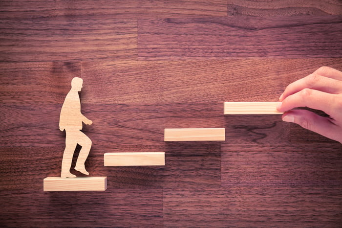 Wooden image of man climbing up some wooden steps against a wooden background