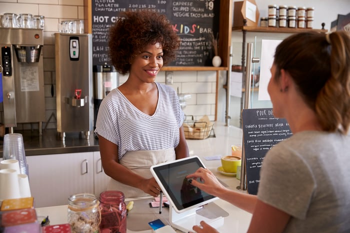 Customer paying with touch screen at coffee shop.