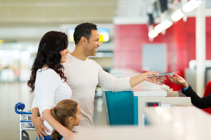 Young happy family handing over tickets at airline counter.