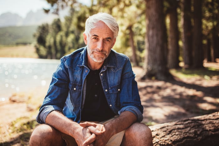 An older man sitting in an outdoor scene.