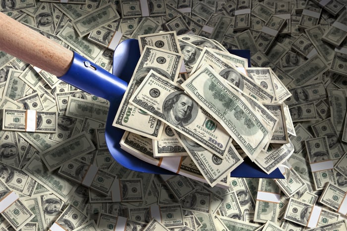 A shovel scooping up piles of cash. 