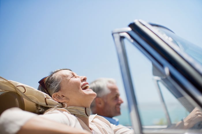 Two happy older folks riding in a convertible