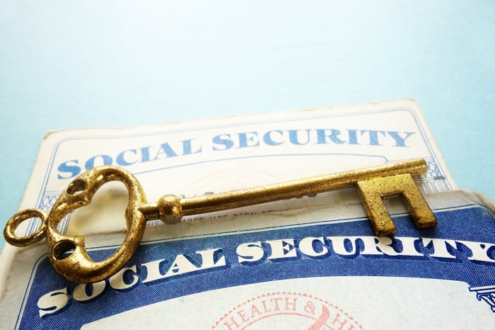 A key sitting atop two Social Security cards, representing a fix for the program. 