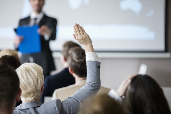 A woman raises her hand at a meeting.