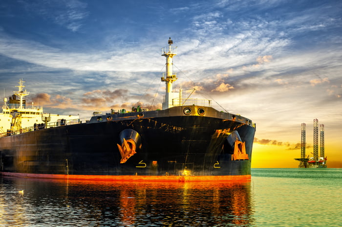 Tanker ship and oil platform on offshore area at sunset.