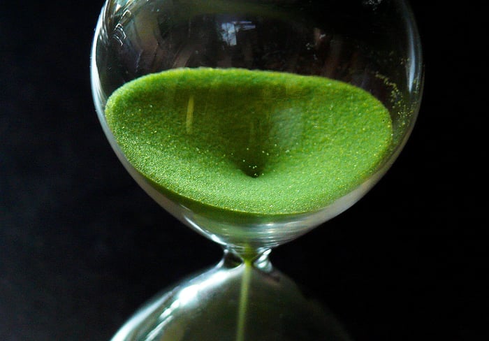 closeup of an hourglass with green sand falling through