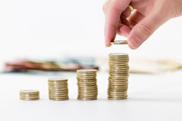 Woman's hand stacking growing piles of coins