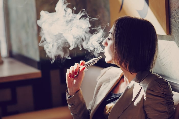 A woman exhales using a personal vapor system.