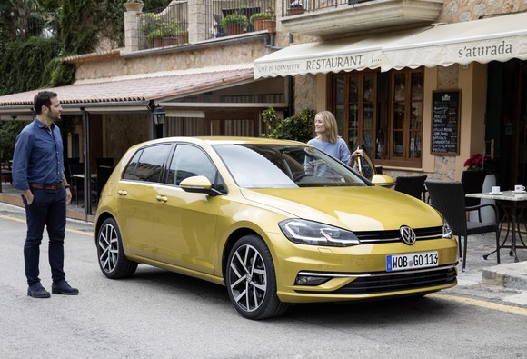 A yellow VW Golf in front of a restaurant.