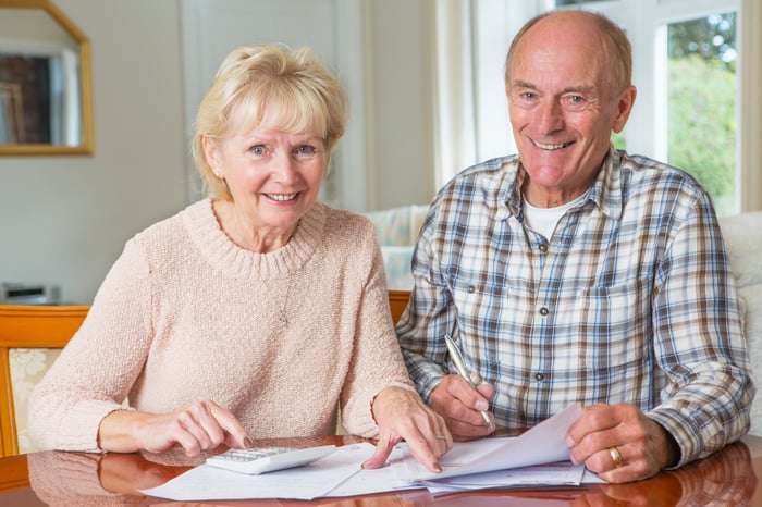 A smiling elderly couple examining their finances. 