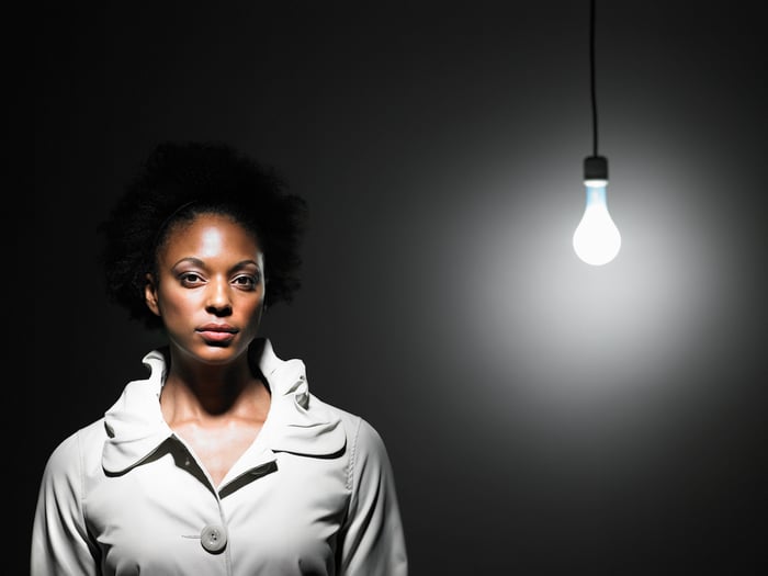 Woman standing near a light bare lightbulb.