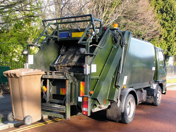 A garbage truck picking up bins. 