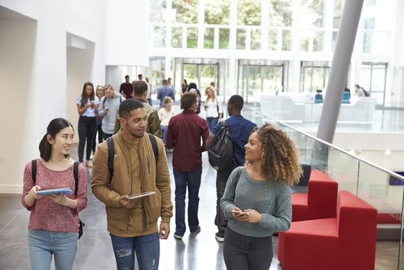 A group of young people walking along an indoor corridor.