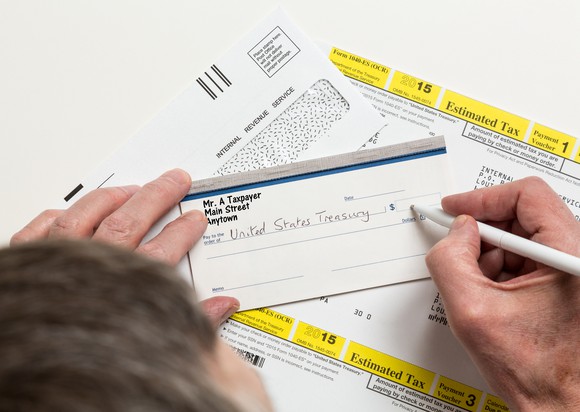 A person filling out a check for their quarterly estimated tax payment to the IRS.