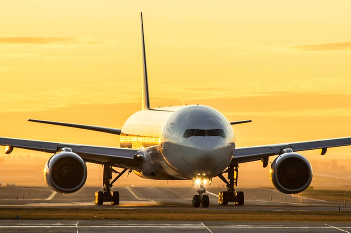 An airplane on the runway at sunset. 