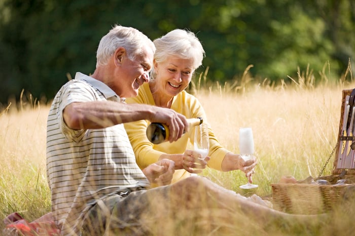 Retired couple having a champagne picnic