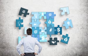 Uomo che guarda i pezzi del puzzle sul muro, con i segni del dollaro e altre immagini di successo