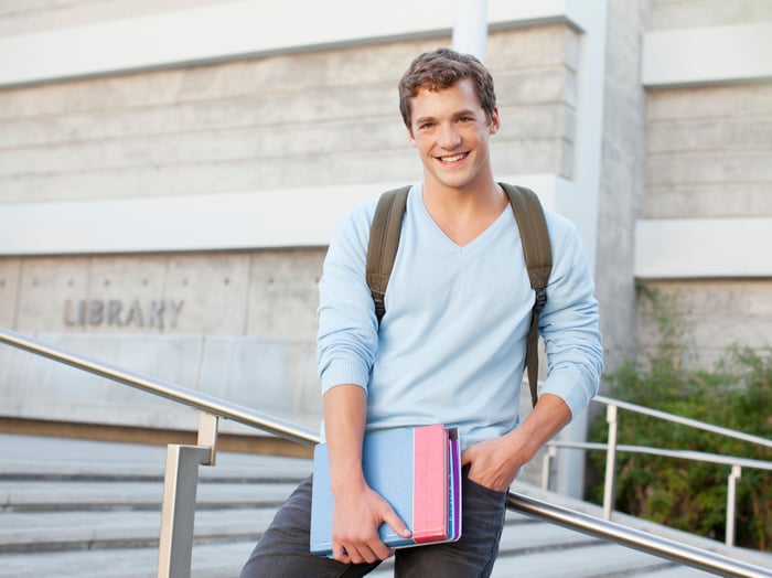 Millenial college students outside library with books and a backpack.