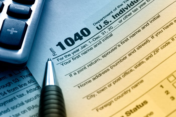 An IRS 1040 tax form next to a calculator and pen.