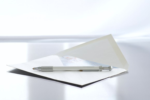 A note cars sits in an envelope with a pent on top of it