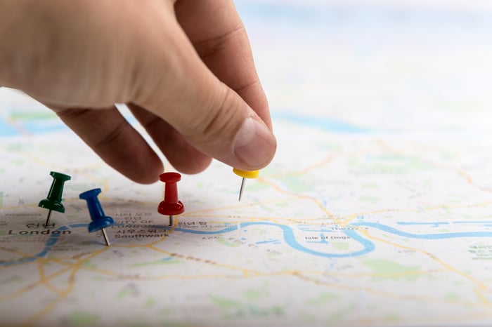 person putting push pins in a road map