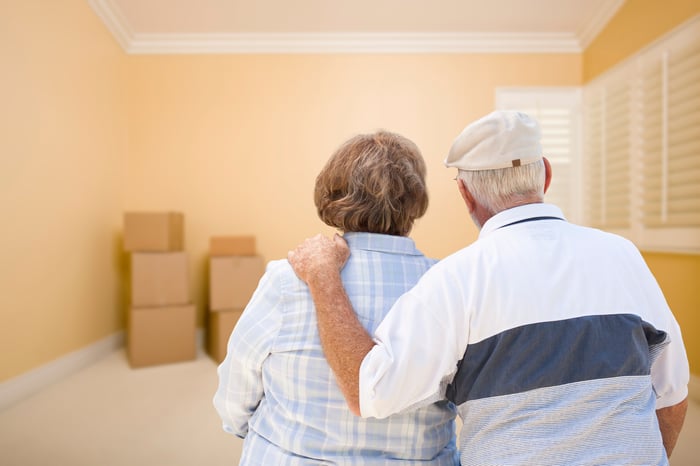 Senior couple in room looking at moving boxes on floor