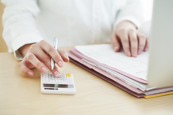 Woman looking over documents and using a calculator.