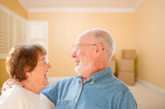 Happy senior couple with moving boxes in the background