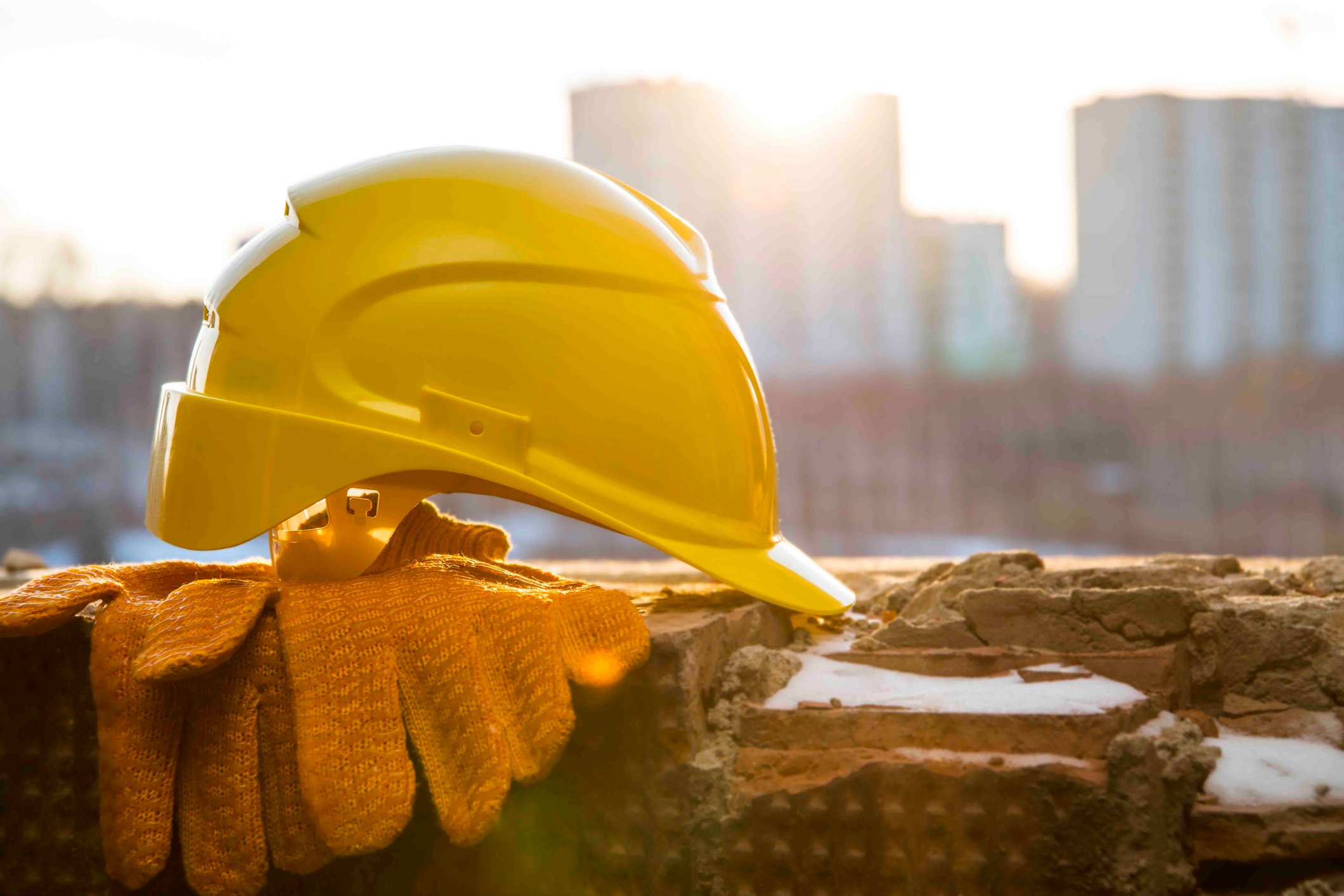 A yellow hard hat sitting on top of gloves on a ledge.