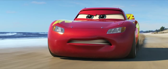 Character Lightning McQueen driving on a beach in Disney's "Cars 3." 