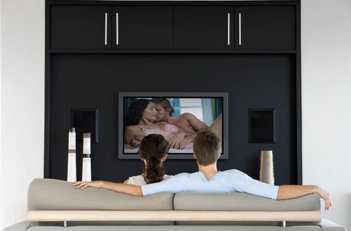 Back view of couple watching romantic movie on television.