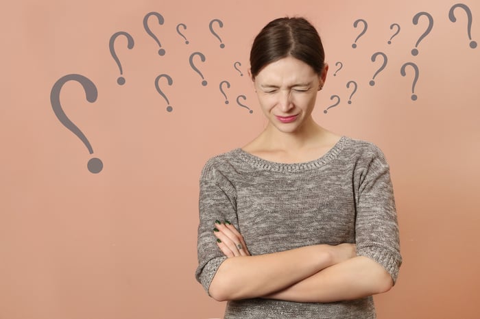 A woman in deep thought with question marks surrounding her head.