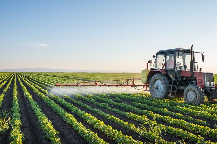 A farmer using a tractor to spray his crop with an insect repellent. 