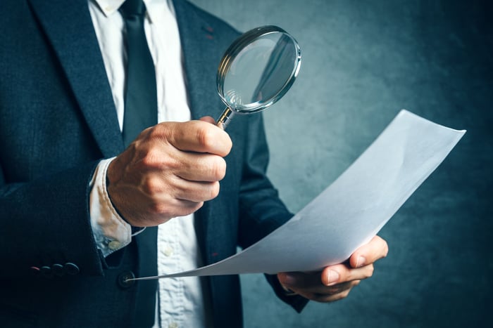 A man inspecting a document with a magnifying glass. 