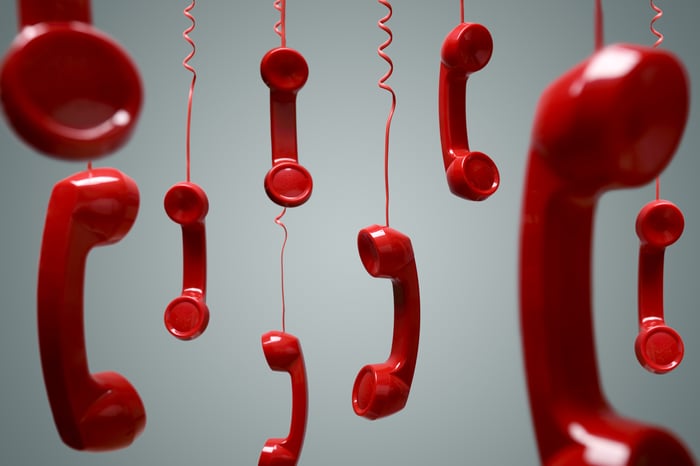 Red telephone receivers dangling in the air.