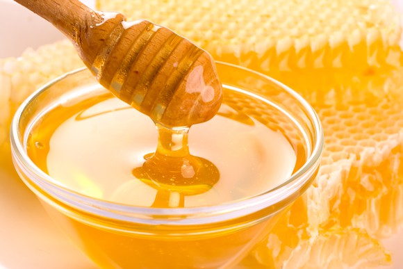 Honey dipper in bowl of fresh honey