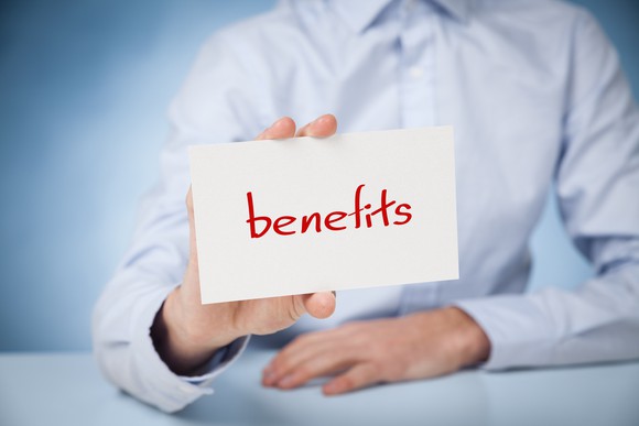 Person holding a card with the word "benefits" written on it