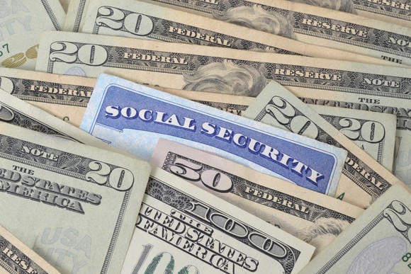 Social Security card nestled among dollar bills