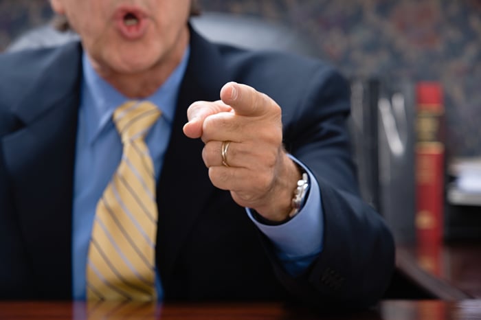 A angry man in a suit points a finger