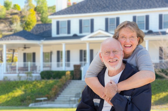 Senior couple smiling outside a large house