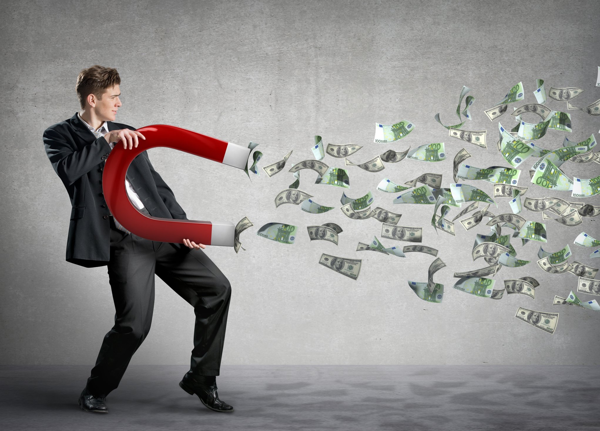 Businessman attracts lots of money with a giant magnet.