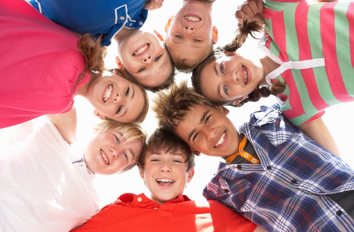 Teenagers in a huddle, smiling down at the camera