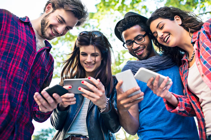 4 friends gathered around their mobile phones