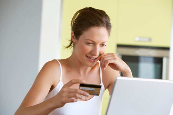 A woman holding a credit card and making a purchase on her laptop.