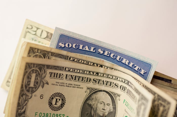 A Social Security car wedged in between cash bills. 