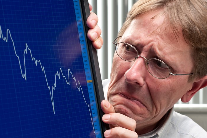 A worried man looks at a plunging stock chart on his computer screen.