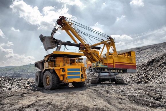 An excavator in an open-pit mine loading a dump truck.