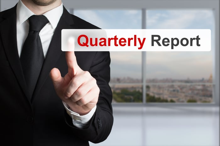 A man in a business suit touching the "quarterly report" tab on a digital screen.